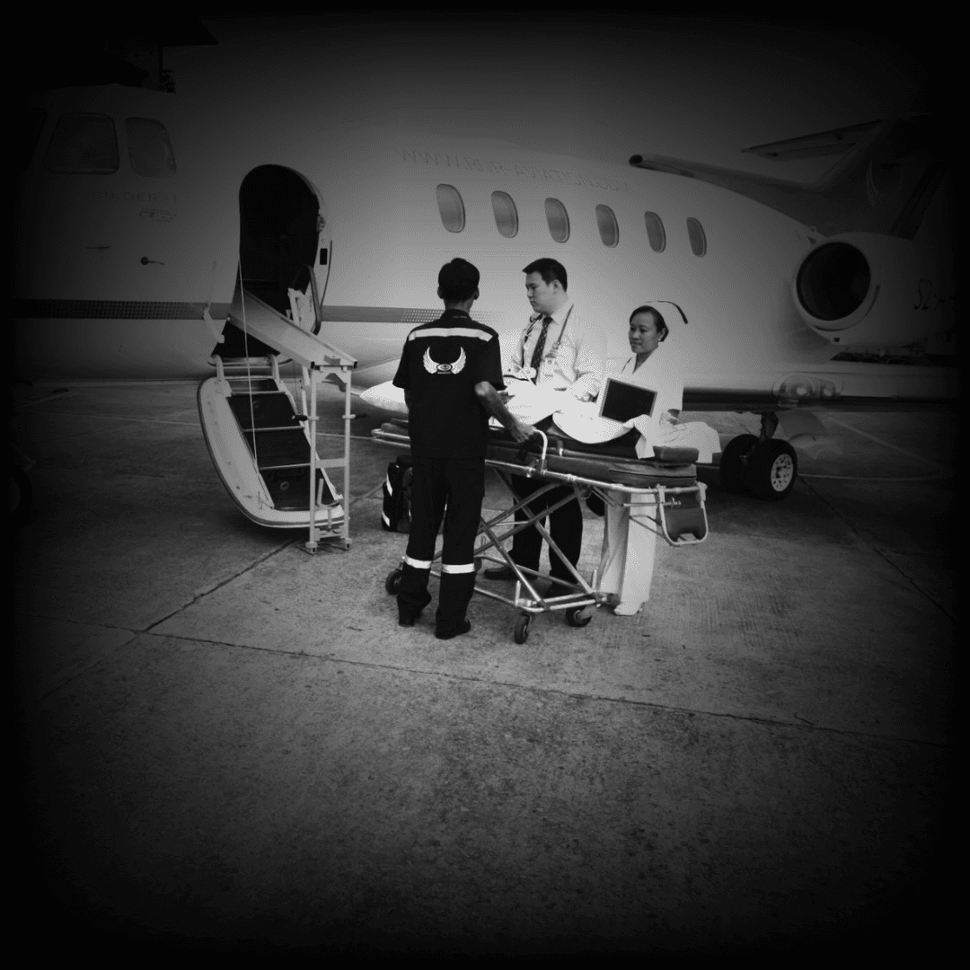 Medical personnel with a stretcher and a small aircraft on an airport tarmac.