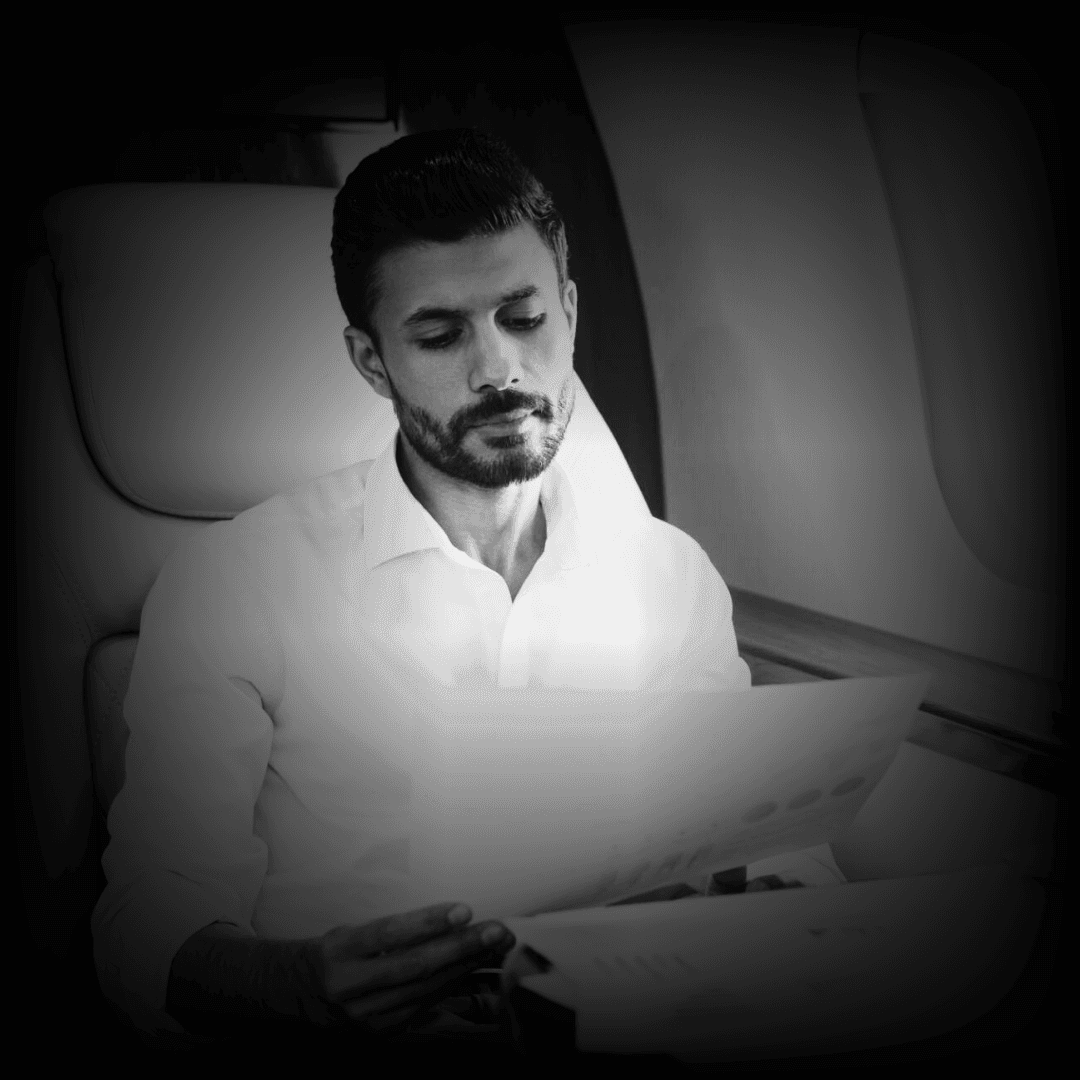 Person wearing a white shirt reading documents while sitting in a cozy airplane seat.